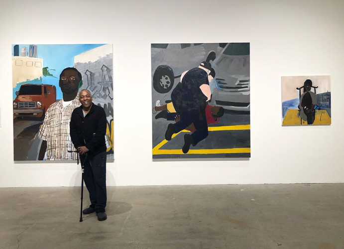 Henry Taylor standing in front of his paintings in the 2019 exhibition "Here" curated by Steven Wong. Courtesy of The Los Angeles Municipal Art Gallery.